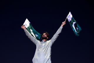 A Pakistani man waves national flags while celebrating the ceasefire agreed between Pakistan and India